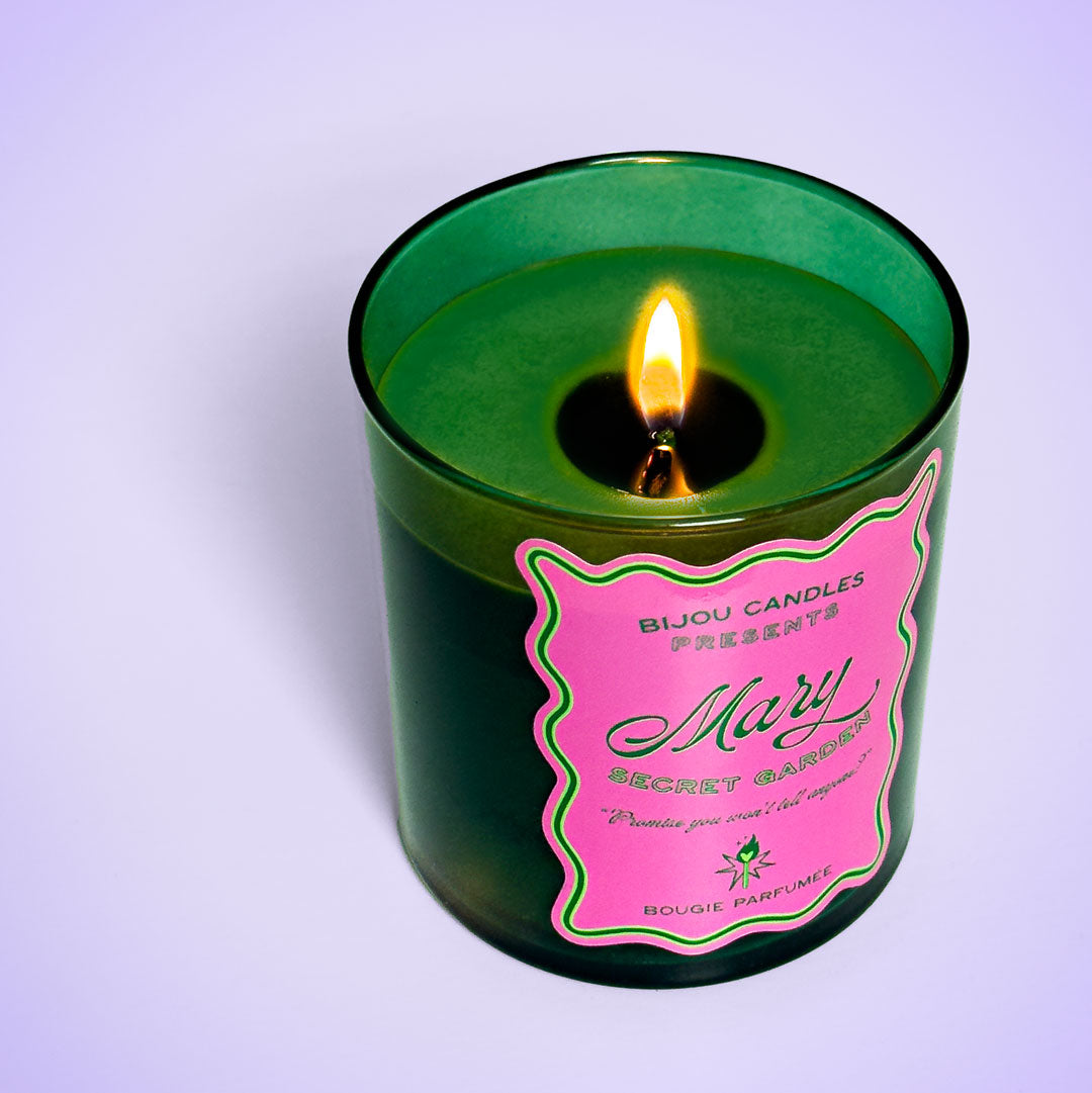Green candle with a pink label on a white background