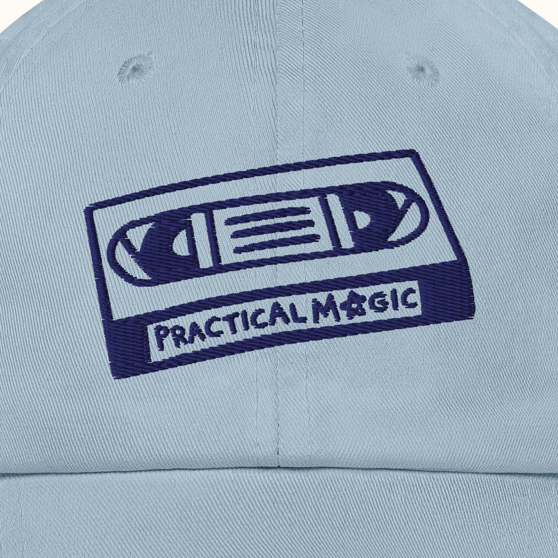 Light blue cap with a cassette tape design and 'Practical Magic' text on a white background
