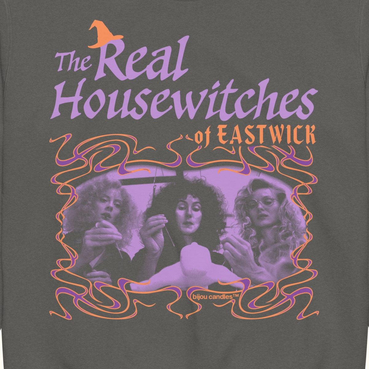 A dark gray crewneck sweatshirt featuring a graphic print for 'The Real Housewives of Eastwick' with purple text, orange accents, and a vintage-style illustration of three women.