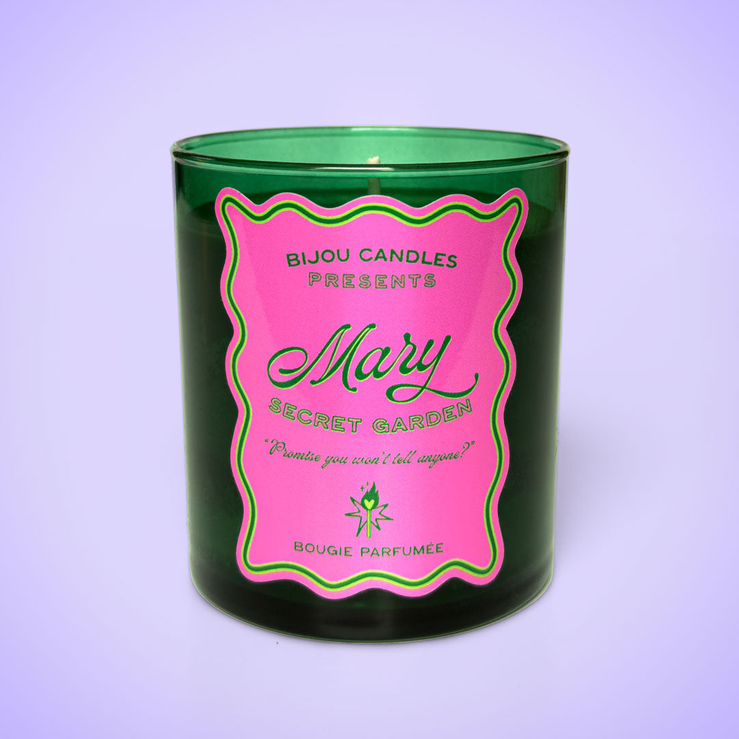 Green candle with a pink label on a white background