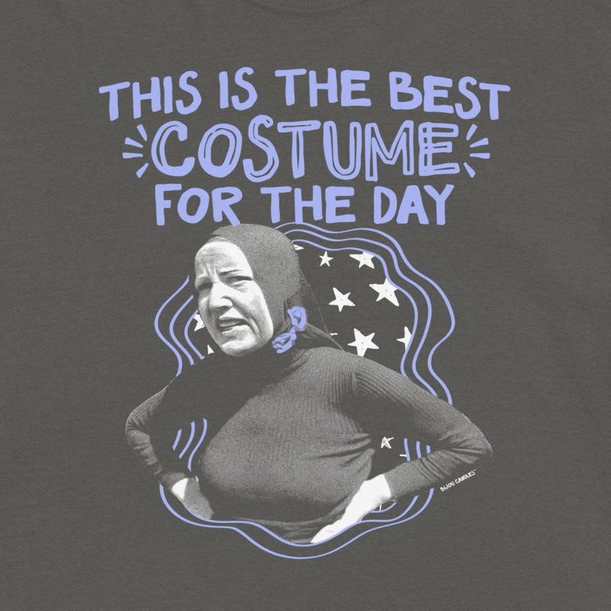 A dark gray graphic t-shirt featuring a humorous print that reads 'THIS IS THE BEST COSTUME FOR THE DAY' above a black-and-white photo of a person in a costume, set against a light cream background.