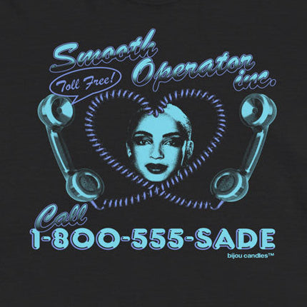 A black short-sleeve t-shirt with a retro-style graphic on the front featuring a woman's face inside a heart, telephone receiver illustrations, and the text 'Smooth Operator Line' and 'Call 1-800-555-SADE' in a bright cyan-blue color, displayed against a light cream background.