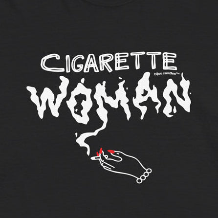 A black short-sleeve graphic t-shirt featuring the text 'CIGARETTE WOMAN' in a stylized white font, with a small illustration of a hand holding a lit cigarette below it, shown flat against a light cream background.