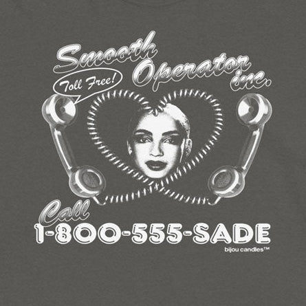 A dark gray short-sleeve t-shirt with a white retro graphic on the front. The graphic features a heart-shaped face, telephone receiver illustrations, and the text 'Smooth Operator Line' and 'Call 1-800-555-SADE'.